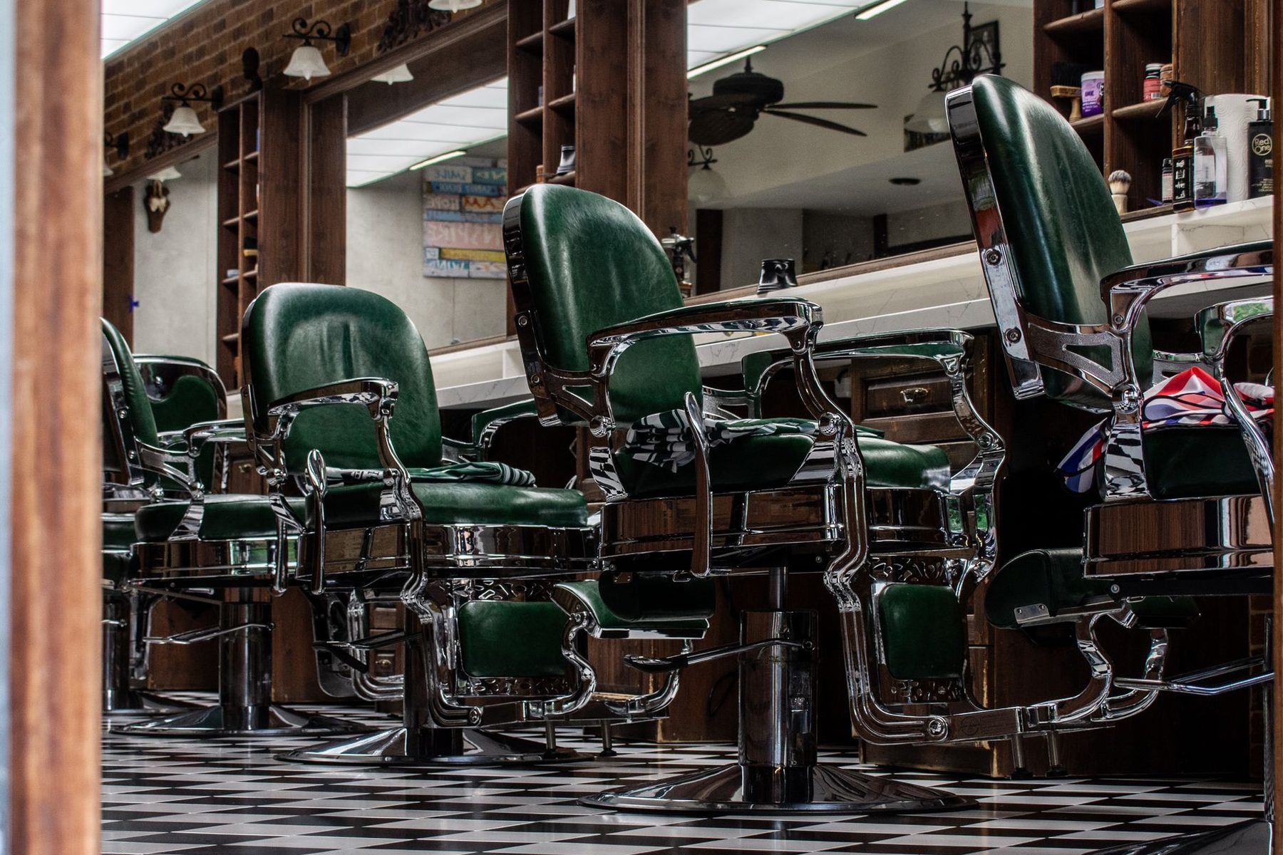 Green leather barber chairs on a checkerboard floor, used in the fictional Hollis Barbershop concept