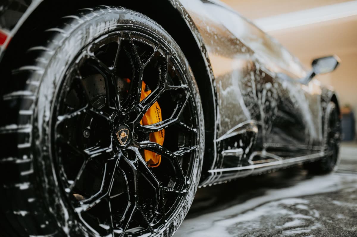 A black alloy wheel covered in foam with a yellow brake caliper showing through, used in the fictional Blackwater Detailing concept