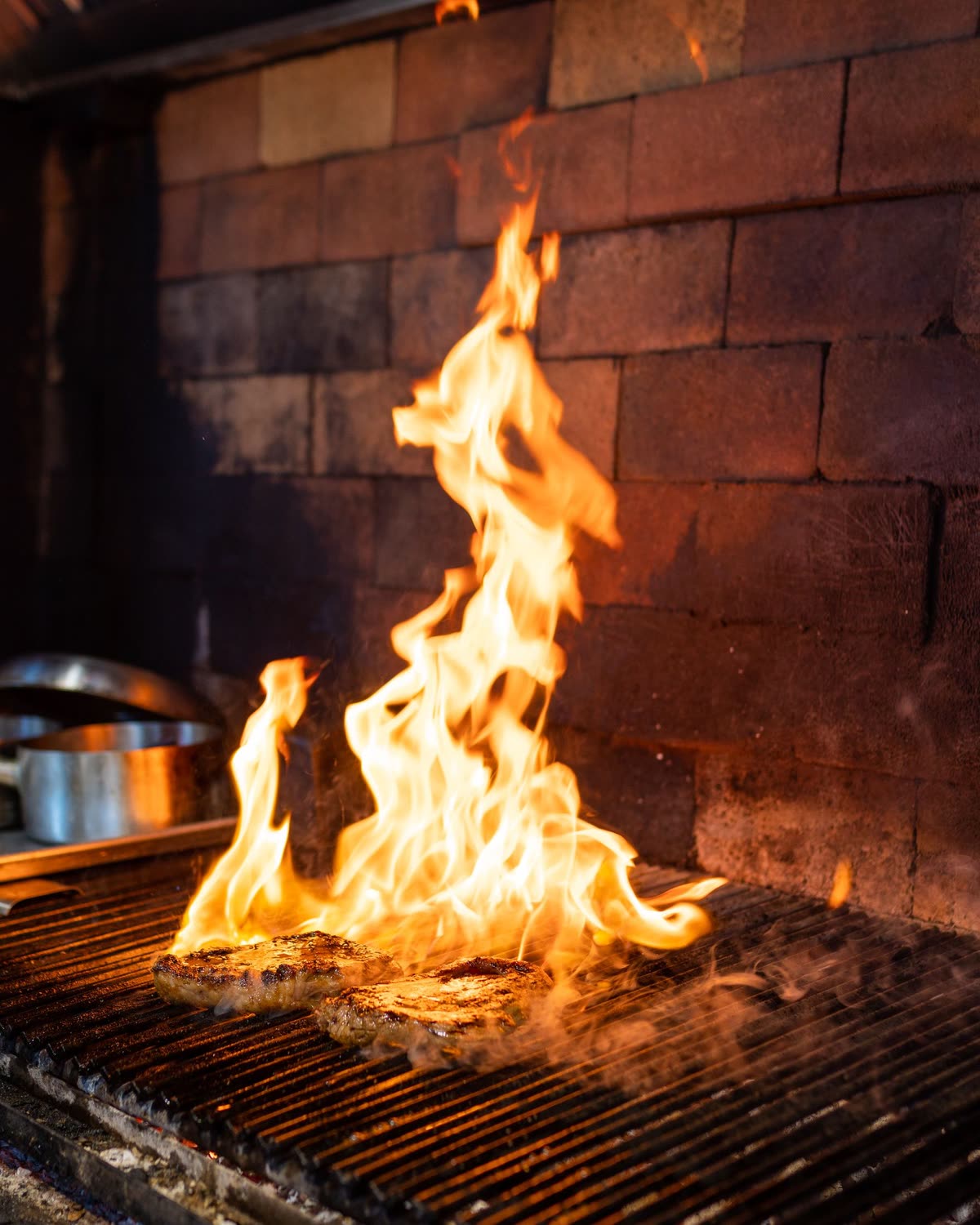 Flames rising over a grill in a brick kitchen, used in the fictional Emberline concept